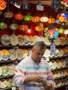 A seller selling traditional Turkish souvenir in the Grand Bazaar. Colorful ceramics and lamps in sale shops in the Market.