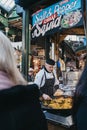 Seller serving paella at a street food stand in Borough Market, London, UK