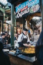 Seller serving paella at a street food stand in Borough Market, London, UK