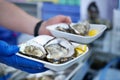 Seller is serving two plates with fresh oysters and sliced lemon. Selective focus