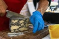 Seller slicing mold cheese on wooden board. Cheese shop Royalty Free Stock Photo