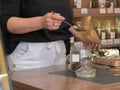 The seller of the store girl pours fragrant tea from different herbs with a spoon from a glass jar with a paper bag. Business