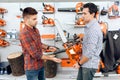 The seller in the store shows the customers a chainsaw. Royalty Free Stock Photo