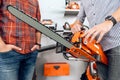 The seller in the store shows the customers a chainsaw. Royalty Free Stock Photo