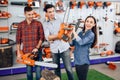 The seller in the store shows the customers a chainsaw. Royalty Free Stock Photo