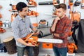 The seller in the store shows the customers a chainsaw. Royalty Free Stock Photo