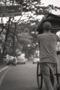 The seller walks to push his food-cart along the street