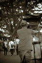 The seller walks to push his food-cart along the street