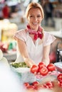 Seller woman offers fresh and organic vegetables at the green market or farmers market stall. tomatos for healthy food in grocery Royalty Free Stock Photo