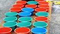 Selling Colorful tubs lined together on a wooden platform. Small plastic tubs filled with soap solution for blowing bubbles