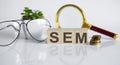 SEM concept on wooden cubes and flower glasses coins and magnifier on the white background