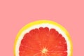 Semi circle slice of ripe juicy red grapefruit on cherry pink background. Citrus fruits summer vitamins