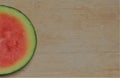 Semi-curcular slice of seedless watermelon, on the edge of a worn bamboo cutting board Royalty Free Stock Photo