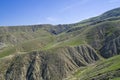 A semi-desert covered with fresh green grass in spring. Clay ravines with traces of soil erosion and weathering