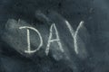 Semi-erased word DAY on black chalkboard. Handwritten word. Fuzzy letters on black surface. The concept of changing the time of