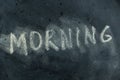 The semi-erased word MORNING on the black chalkboard. Handwritten word. Fuzzy letters on black surface. The concept of changing