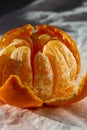 Semi-peeled tangerine clementine on a white cotton tablecloth