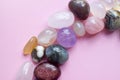 Semi-precious beautiful stones of bright colors lie on a pink background. Amethyst, rose quartz, agate, apatite, aventurine,