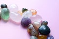 Semi-precious beautiful stones of bright colors lie on a pink background. Amethyst, rose quartz, agate, apatite, aventurine,