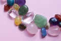 Semi-precious beautiful stones of bright colors lie on a pink background. Amethyst, rose quartz, agate, apatite, aventurine,