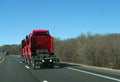 Semi tractor hauling three semi trucks, red, on highway