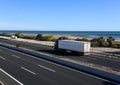 Semi-trailer truck driving along highway. Traffic on motorway and road near sea. Royalty Free Stock Photo