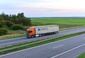 Semi-trailer truck SCANIA by `HOPTRANS` logistics operator driving along highway on sunset background. Goods Delivery by roads. Royalty Free Stock Photo