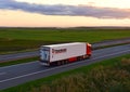 Semi-trailer truck VOLVO by ÃÂ«TRANSCOMÃÂ» cargo company driving along highway on sunset background. Goods Delivery by roads. Royalty Free Stock Photo