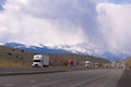 Semi tricks convoy on devided highway on hills snowy mountains Royalty Free Stock Photo