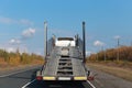 Semi truck with empty car carrier trailer running on the road in sunny autumn day.back view.car transporter.transport concept,work