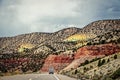 Semi truck on highway through badlands of Utah withcolorful red rock cliffs and chalk mountains