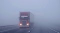 A semi truck jackknifed on a highway partially hidden in a dense fog Royalty Free Stock Photo