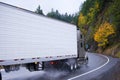 Semi truck and reefer trailer wheels in autumn rain dust