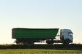 Semi-truck with tipping cargo trailer transporting sand from quarry driving on highway hauling goods in evening Royalty Free Stock Photo