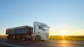 Semi-truck with tipping cargo trailer transporting sand from quarry driving on highway hauling goods in evening Royalty Free Stock Photo