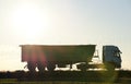 Semi-truck with tipping cargo trailer transporting sand from quarry driving on highway hauling goods in evening Royalty Free Stock Photo