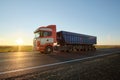 Semi-truck with tipping cargo trailer transporting sand from quarry driving on highway hauling goods in evening Royalty Free Stock Photo