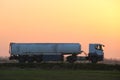 Semi-truck with tipping cargo trailer transporting sand from quarry driving on highway hauling goods in evening Royalty Free Stock Photo