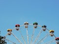 Semicircular fragment of a Ferris wheel with multi-colored booths against a clear blue sky.