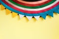 Semicircular handmade cloth stitched from colorful stripes on top of bright pastel yellow background. Royalty Free Stock Photo