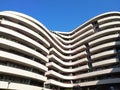 The semicircular white building with curved balconies and terraces on the background of blue sky. modern construction of houses