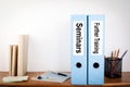 Seminars and Further Training binders in the office. Stationery on a wooden shelf