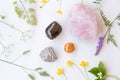 Semiprecious gemstones or crystals on white background with wild summer flowers.