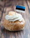 Semla, fastelavnsbolle, fastlagsbulle. Decorated with an Estonian flag. On a wooden table with a dark background.