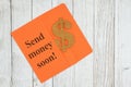 Send money soon text with dollar sign symbol with orange envelope on textured wood desk