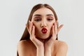 Sending kisses. Young beautiful brunette girl with red lips makeup posing over grey studio background. Concept of beauty Royalty Free Stock Photo