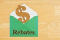 Rebates text with dollar sign symbol with green envelope on textured wood desk Royalty Free Stock Photo