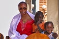 African mother with his two children on knee looking at camera. Smiling, one child shy Royalty Free Stock Photo