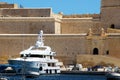 Senglea, Malta, July 2016. Fortified walls with entrance gates and a large yacht at the pier.