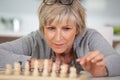 senile old woman playing game chess alone